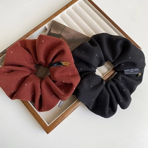 Detailed macro view of two fabric scrunchies with Blind For Love tags on wooden tray