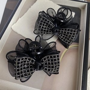 Détail de pinces à cheveux à nœud en maille noire avec strass et structure acrylique