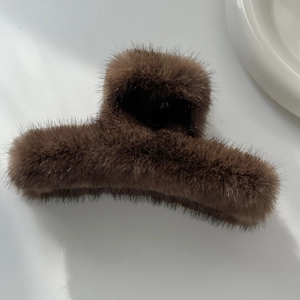 Gros plan d'une grande pince à cheveux en peluche marron foncé avec fourrure douce