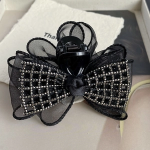 Vue détaillée de la pince à cheveux avec nœud en maille noire et strass scintillants