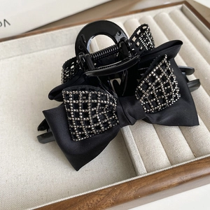 Detailed macro view of black satin bow hair claw clip with sparkling rhinestones decoration