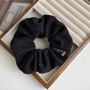 Detail of black polka dot hair scrunchie with Lucky pendant and logo fabric tag