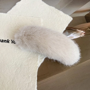 Detailansicht der flauschigen cremefarbenen Kunstfell-Textur der modischen Bananen-Haarklammer
