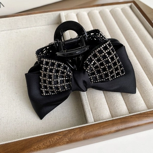 Detail of elegant black satin bow hair claw clip with sparkly silver rhinestones