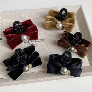 Detail of colorful bow hair claws with elegant center pearls and gold charms on a tray
