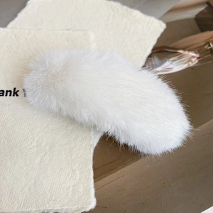 Detailaufnahme der weichen weißen Plüschtextur dieser modischen Bananen-Haarklammer