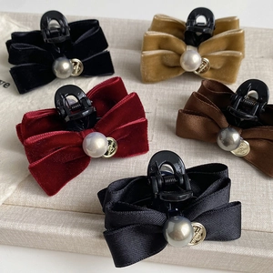 Close-up of velvet and satin bow hair clips with large pearl accents and gold charms