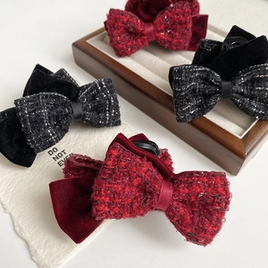 Close-up of elegant tweed bow hair claw clips in red and grey velvet fabrics