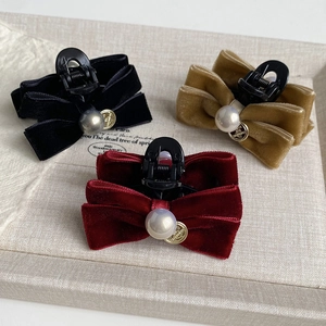 Detailed view of velvet bow hair claws with large pearls in black, red, and champagne