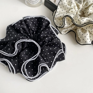 Detail view of black and beige polka dot scrunchies with elegant contrast edge stitching
