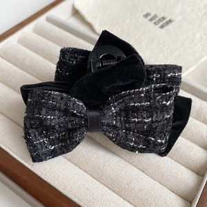 Close-up of elegant black tweed and velvet bow hair claw clip in a luxury jewelry box