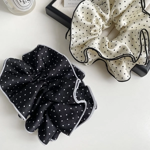 Close-up of black and white polka dot satin scrunchies with elegant ruffled edges
