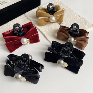 Detail view of velvet bow hair clips with white pearls and gold love pendants