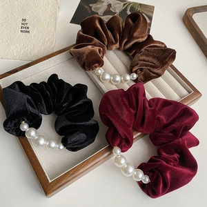 Detail of velvet scrunchies in black, brown and wine red with pearl embellishments