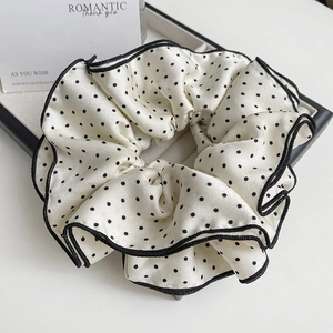 Detailed view of large polka dot scrunchie with satin texture and black hemmed edge