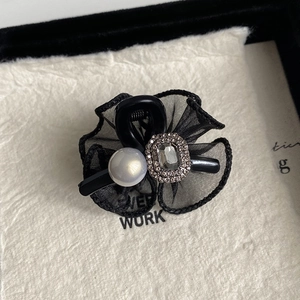 Macro shot of bow hair clip featuring black mesh petals with crystal and pearl details