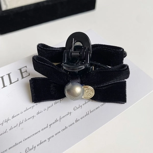 Detail of a black velvet bow hair clip with gray pearl and vintage gold coin pendant