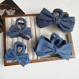 Lot de barrettes à nœuds en denim bleu avec étiquettes dorées sur un plateau en bois