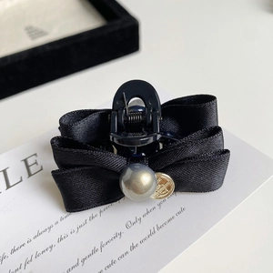 Detail of elegant black ribbon bow hair clip with grey pearl and golden charm