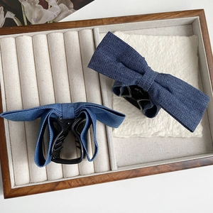 Détail de la texture en denim bleu des pinces à cheveux à nœud dans un plateau à bijoux