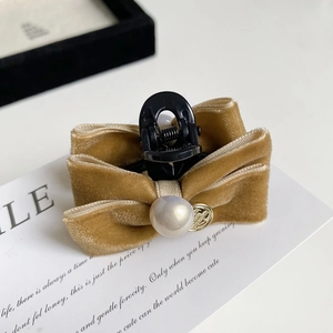 Detail of velvet bow hair claw clip featuring a large cream pearl and gold pendant decoration