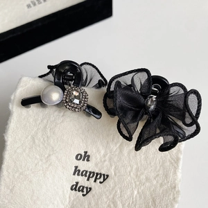 Detail showing two vintage black bow hair clips with pearls and rhinestones on display