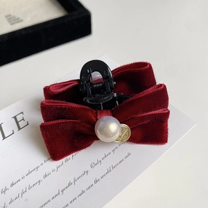 Detailed close-up of a burgundy velvet bow hair claw clip with a large central pearl accent