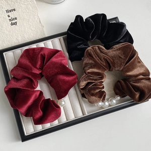Macro detail of velvet scrunchies with white pearls on a white jewelry display tray