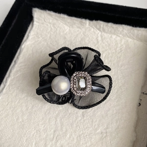 Detail of elegant black mesh flower clip with crystal gem and pearl embellishment