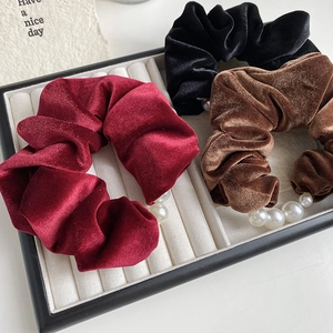 Detail of velvet pearl scrunchies in wine red, black, and coffee on a jewelry tray