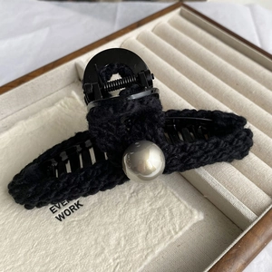 Vue détaillée de la pince à cheveux crochetée noire avec une grande perle élégante