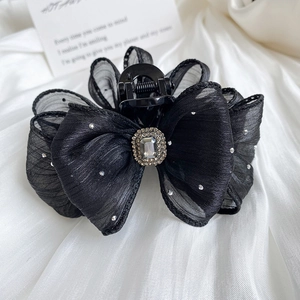 Detailed close-up of a black mesh bow hair claw with rhinestones and central gem