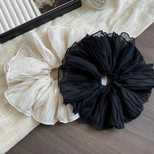 Detail of oversized ruffled scrunchies in cream and black pleated chiffon fabric