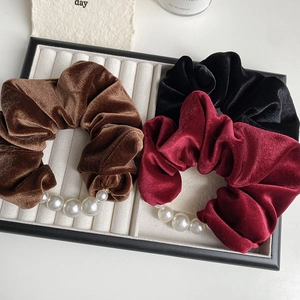 Detailed view of elegant velvet hair scrunchies with pearls in brown, burgundy and black