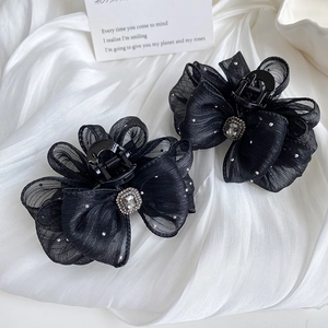 Detail of black organza bow hair claw clip with white dots and sparkling center rhinestone