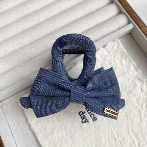 Détail de la pince à cheveux noeud en denim bleu avec étiquette métallique dorée