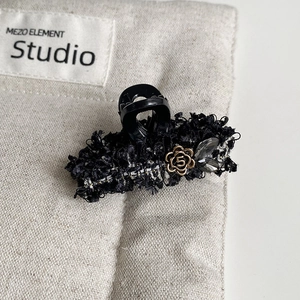 Detail of tweed hair claw with gold camellia flower and rhinestone accents