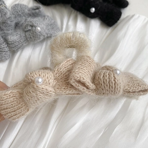 Close-up of knit bow shark clip with white pearls and soft textured fabric detail