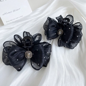 Elegant black organza bow hair clips with pearls and crystals on white silk background
