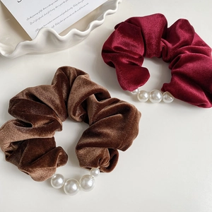 Close-up of wine red and brown velvet hair scrunchies with elegant large pearl accents