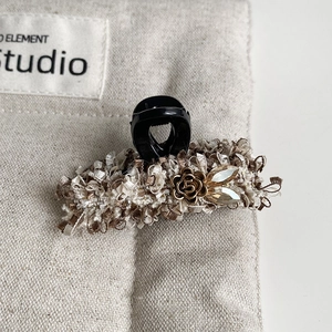 Detail of tweed fabric hair claw with vintage metal flower and sparkling rhinestones