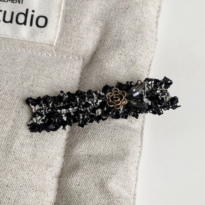 Detailed view of tweed hair claw clip with golden camellia flower and numeral 5 accent