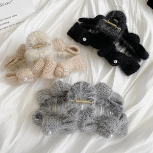 Detail view of knitted bow hair claws with pearl accents in beige black and grey