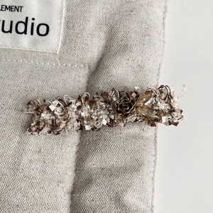 Detail of tweed hair clip with metallic flower, crystal inlay and retro number 5 design