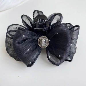 Close-up of black tulle mesh bow hair claw clip with crystal rhinestone centerpiece decoration