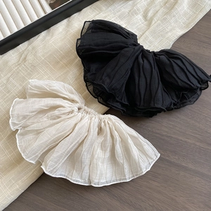 Detail showing oversized pleated scrunchies in black and beige with soft chiffon texture