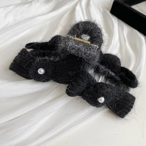 Detailed view of black knitted bow hair claw clip with elegant pearl embellishments