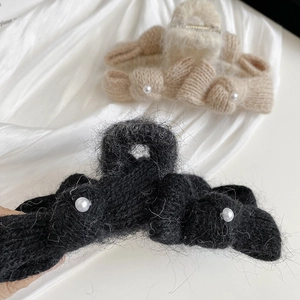 Close-up of knitted bow hair claws with elegant pearl embellishments and soft texture
