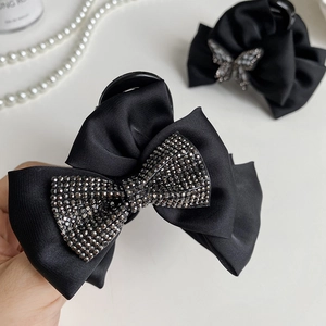 Detail of elegant black satin bow hair claw with sparkling rhinestones and pearls