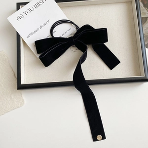 Close-up of black velvet bow hair tie with long ribbons and a gold metal detail